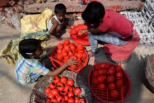 Children colour earthen pots along a roadside, at Kumhar Gram (Potter's Village) in New Delhi. PHOTO: AFP