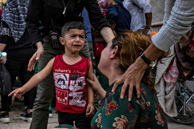A woman and a child react as the body of a man killed during Turkish shelling near the Syrian Kurdish town of Ras al-Ain arrives at a hospital in the nearby town of Tal Tamr. PHOTO: AFP