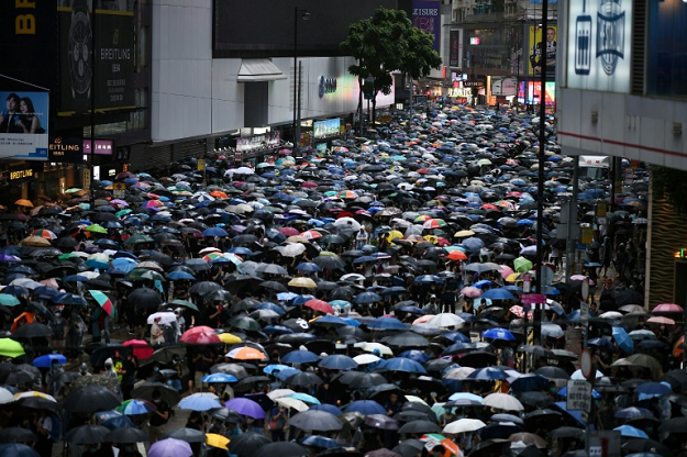 Large crowds marched through torrential rain in unsanctioned rallies on both sides of Victoria Harbour Sunday afternoon. PHOTO: AFP