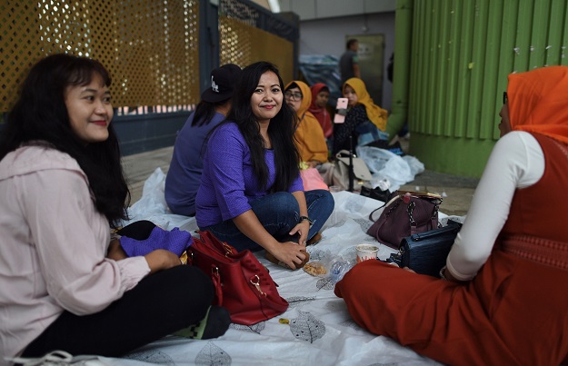 Indonesian migrant worker Marsanah sitting with her friends on their day off at Victoria Park in Hong Kong (Photo: AFP)