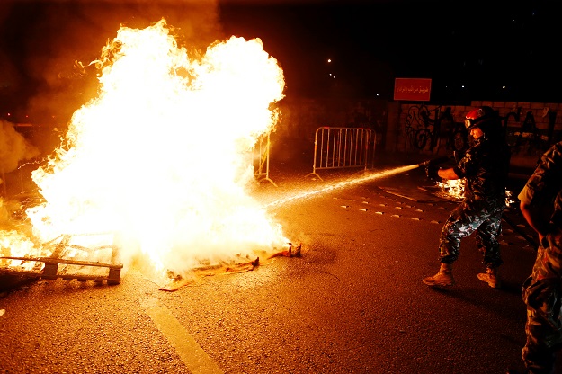 A member of the Lebanese general security extinguishes fire during a protest. PHOTO: Reuters