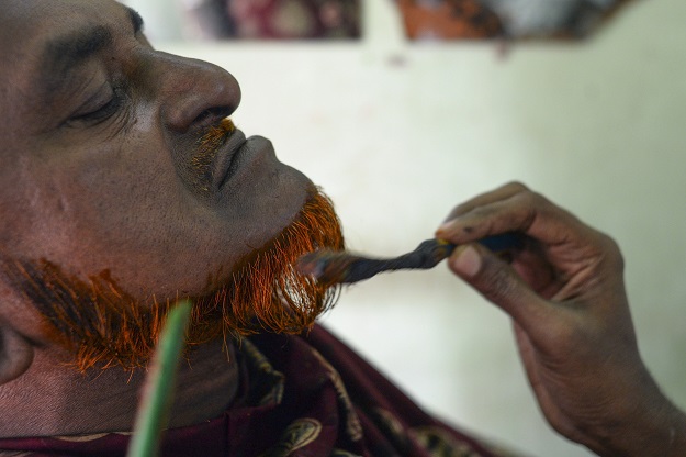 Barber Mohammad Shadat Hossain applies henna to the beard of his client Abdur Rahman in Dhaka (Photo: AFP)