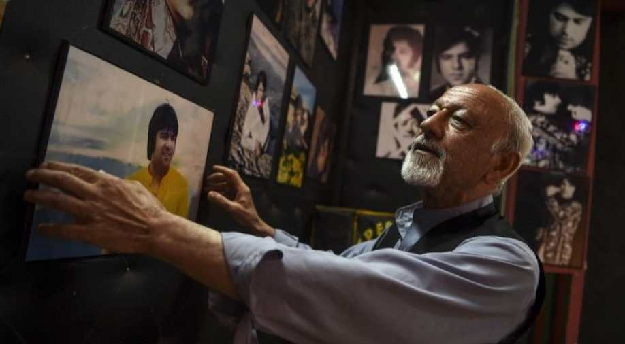 Poet Safiullah Sobat looks on as he hangs a picture of Ahmad Zahir. PHOTO: AFP