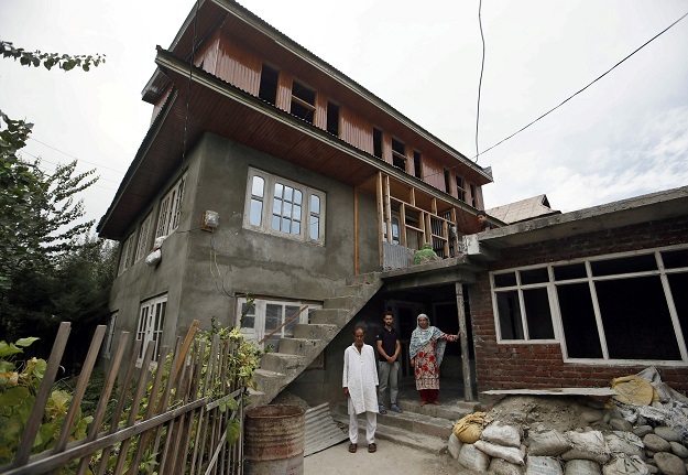 Mohammad Maqbool Malik, Haseena Malik and Danish Maqbool Malik, parents and brother of Uzair Maqbool Malik pose for a picture outside their house in south Kashmir's Shopian town. (Photo: Reuters)