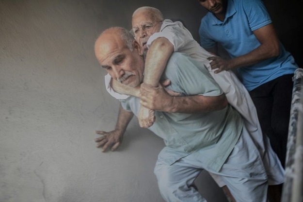 An elderly man is evacuated from a building in the Turkish border town of Akcakale after it was hit by a rocket reportedly fired from Syria. PHOTO: AFP