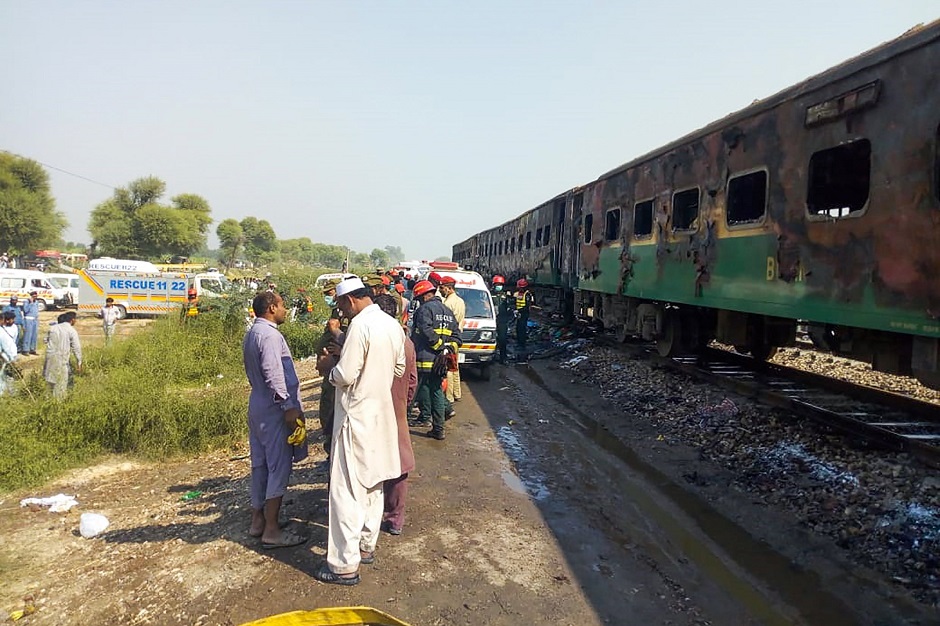 Rescue workers gather beside the burnt-out train carriages after the passenger train caught on fire near Rahim Yar Khan in Punjab (Photo: AFP)