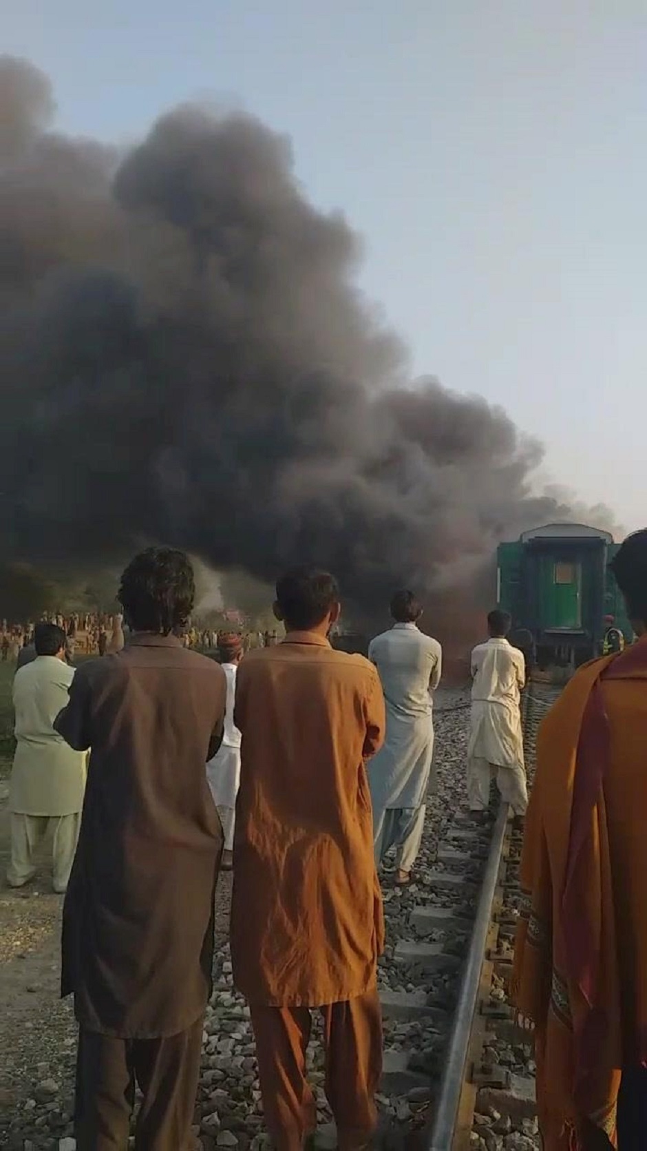 Men look at the burning train (Photo: Reuters)