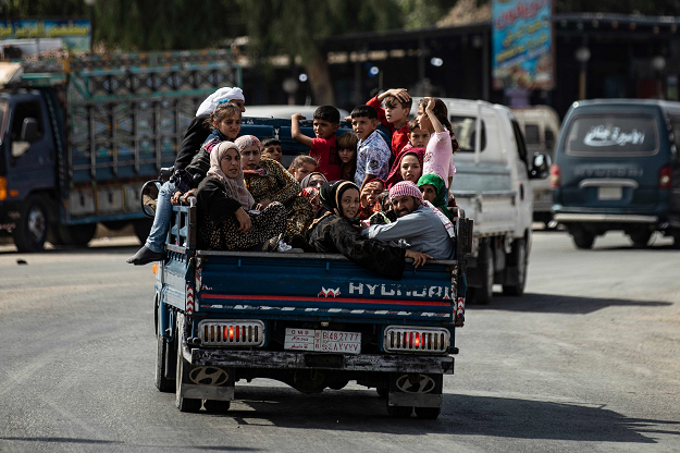 Displaced Syrians sit in the back of a pick up truck as Arab and Kurdish civilians flee amid Turkey's military assault on Kurdish-controlled areas in northeastern Syria, on October 11, 2019 in the Syrian border town of Tal Abyad. PHOTO: AFP