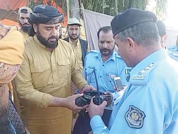 JUI-F members hand over a gun found on a man to the police. PHOTO: PPI/EXPRESS