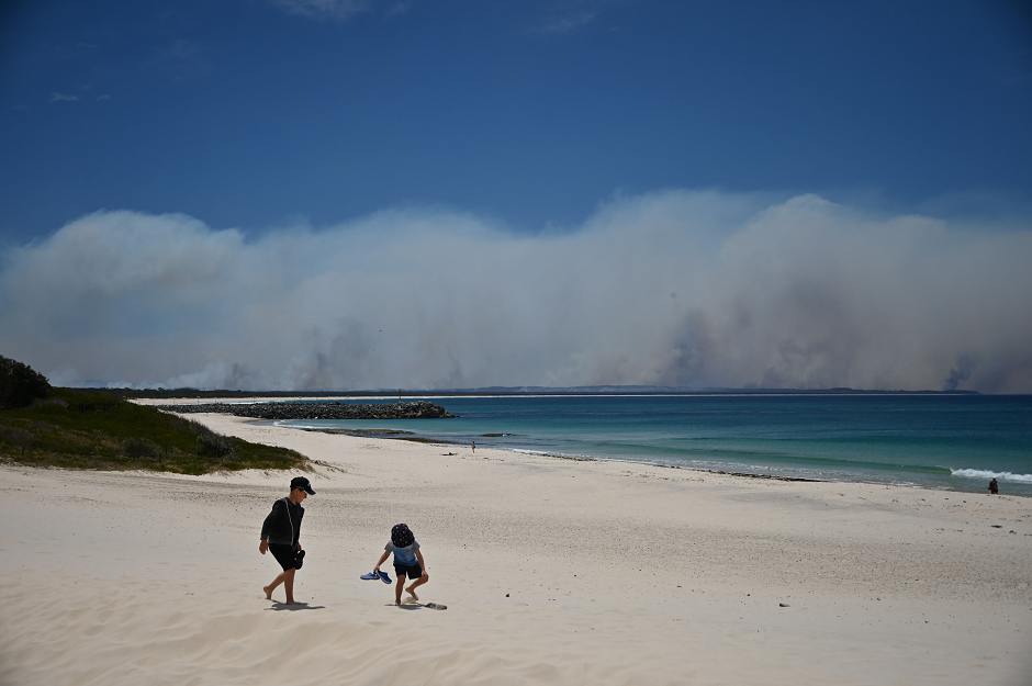 Bushfires burn in the distance as children play on a beach in Forster, 300km north of Sydney on November 9, 2019, as firefighters try to contain dozens of out-of-control blazes that are raging in the state of New South Wales. PHOTO: AFP