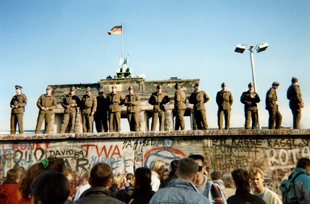 In this file photo taken on November 11, 1989 East German border guards stand on a section of the Berlin wall with the Brandenburg gate in the background in Berlin (Photo: AFP)