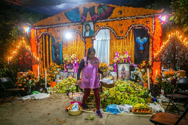 A woman stands near offering for the celebration of the Day of the Dead (Photo: AFP)