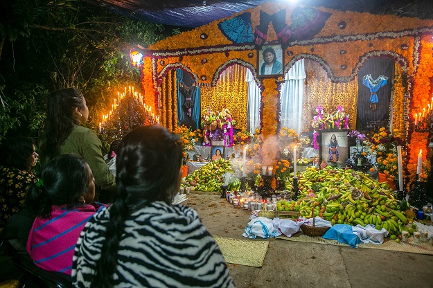 Women look at offerings for the celebration of the Day of the Dead (Photo: AFP)