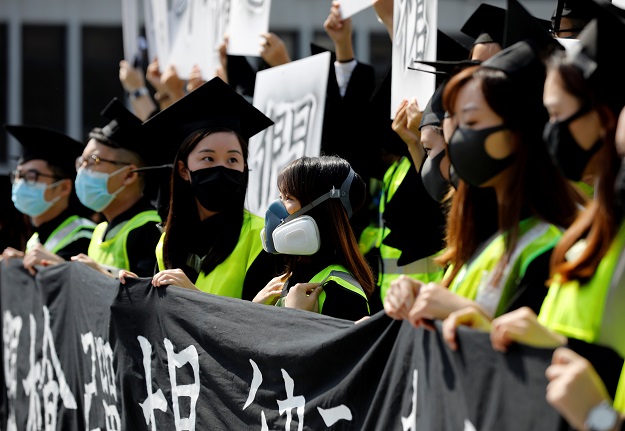Graduates wearing masks hold an anti-government rally after their graduation ceremony. PHOTO: Reuters