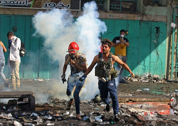 Iraqi protesters run from tear gas during clashes with security forces in Baghdad earlier this week. PHOTO: AFP