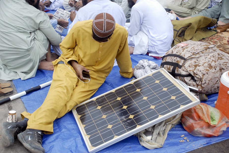 Azadi March' participant uses solar pannel to charge his phone. PHOTO ONLINE.