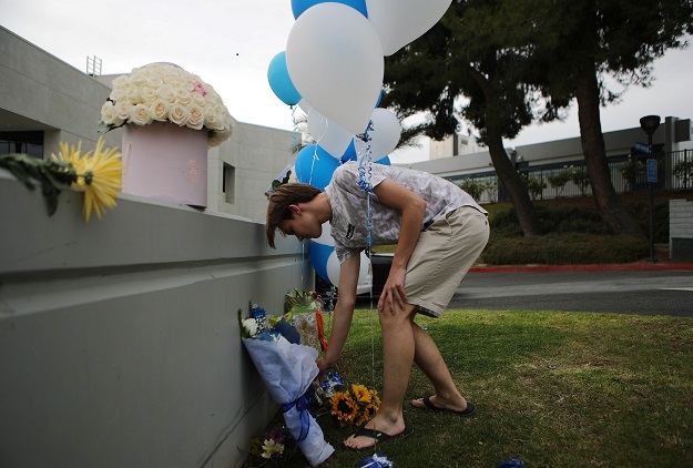 A young man lays flowers at a makeshift memorial in front of Saugus High School the day after a deadly shooting. PHOTO: AFP