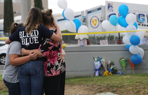 A Saugus High School student (2nd L) is embraced as she visits a makeshift memorial in front of the school for victims of the shooting. PHOTO: AFP