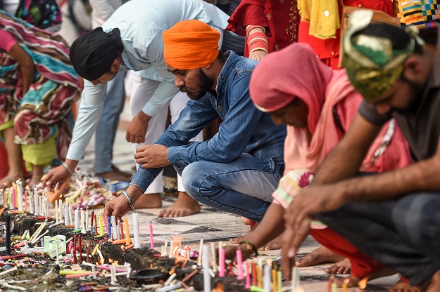Sikh devotees light candles as they pay their respect on the occasion of the 550th birth anniversary of Sikhism founder Guru Nanak Dev. PHOTO: AFP