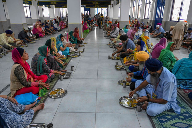 Sikh pilgrims have their lunch at a shrine in Nankana Sahib, some 75 kms west of Lahore on November 7, 2019, on the occasion of the 550th birth anniversary of Guru Nanak Dev. - A corridor that will allow Sikhs to cross from India into Pakistan to visit one of the religion's holiest sites is set to open on November 9, with thousands expected to make a pilgrimage interrupted by decades of conflict. PHOTO: AFP
