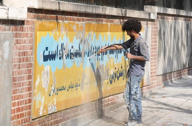 A file photo taken on September 29, 2019 shows a worker using a water jet cleaner to erase a mural painting on the wall of the former US embassy in the Iranian capital Tehran (Photo: AFP)