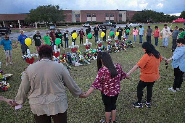 Mourners pray around a memorial in front of Santa Fe High School on May 21, 2018 in Santa Fe, Texas. The makeshift memorial honors the victims of the May 18 shooting when 17-year-old student Dimitrios Pagourtzis entered the school with a shotgun and a pistol and opened fire, killing 10 people. PHOTO: AFP