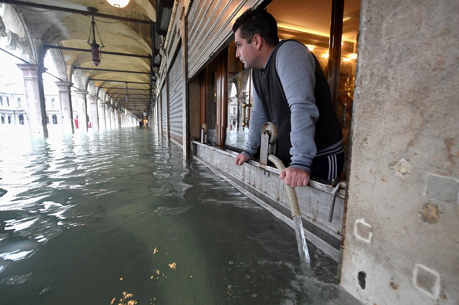 A man pumps water from a shop at the flooded St. Mark's Square. PHOTO: Reuters