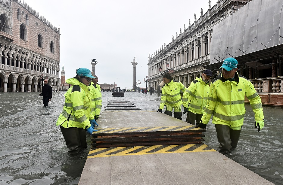 Workers dismantle a makeshift walkway over the flooded St. Mark's Square. PHOTO: Reuters