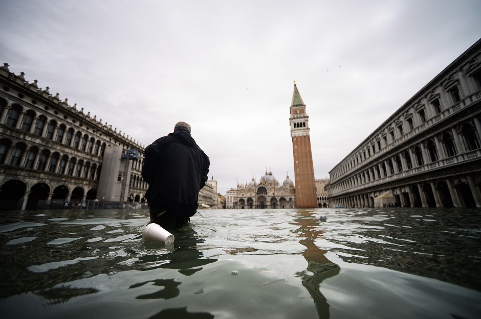 A man walks across the flooded St. Mark's Square, with St. Mark's Basilica (Rear L) and the Bell Tower. PHOTO: AFP