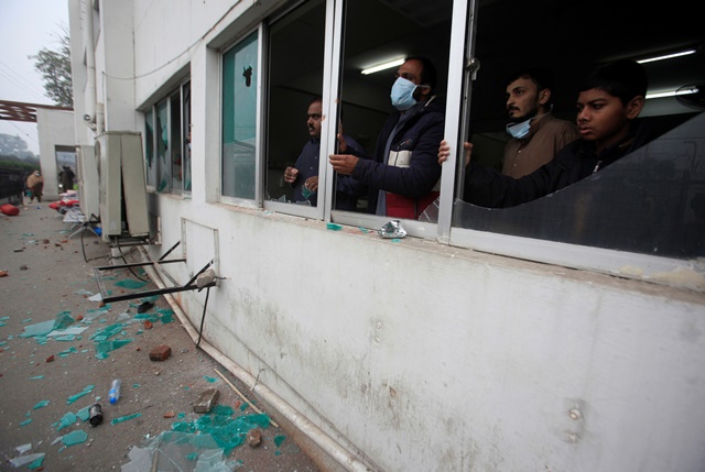 Men stand as they look outside from a broken windows after a group of lawyers stormed the Punjab Institute of Cardiology (PIC) in Lahore, Pakistan December 11, 2019. REUTERS/Mohsin Raza