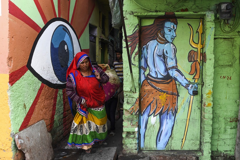 A woman walks out of an alleyway adorned with murals painted by artists from 'Delhi Street Art' group. PHOTO: AFP