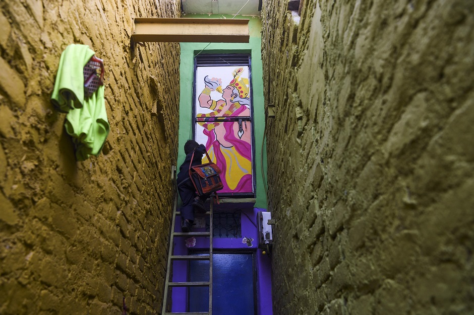 A boy climbs up a ladder to enter a home adorned with a mural. PHOTO: AFP