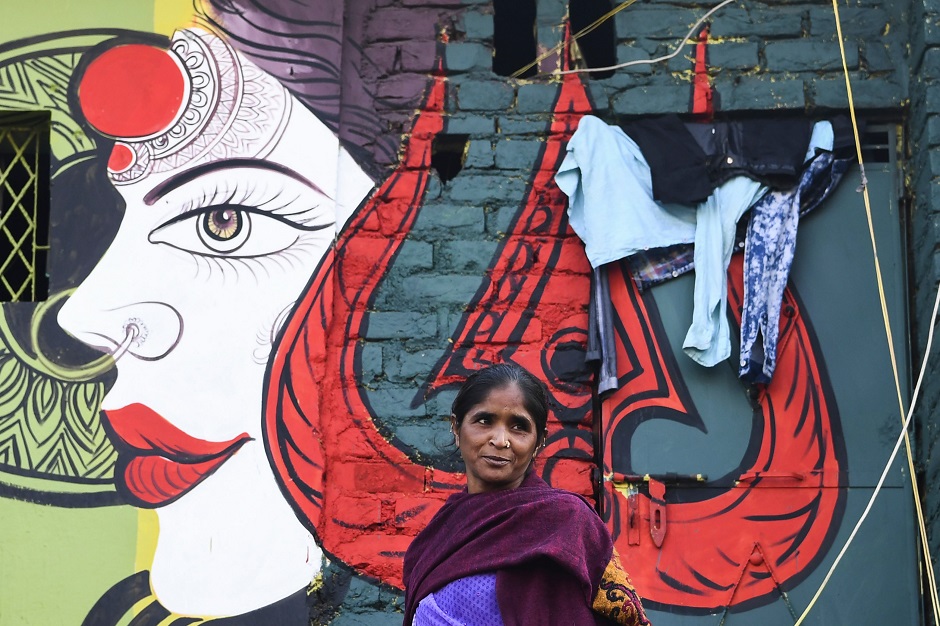 A woman leaves her home adorned with a mural painted by artists from 'Delhi Street Art' group at the Raghubir Nagar slum in New Delhi. PHOTO: AFP