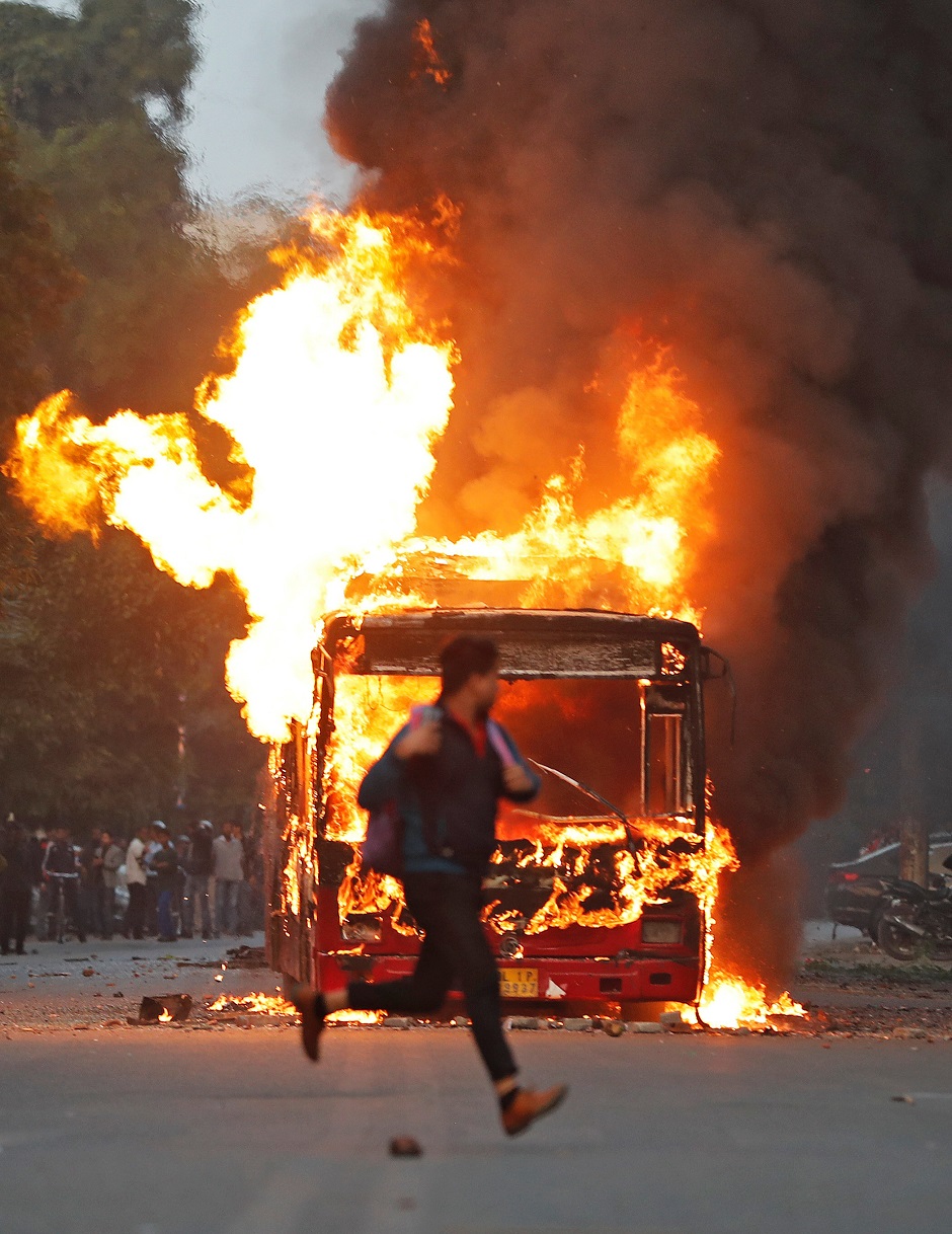 A man runs past a burning bus that was set on fire by demonstrators during a protest against a new citizenship law, in New Delhi. PHOTO: REUTERS 
