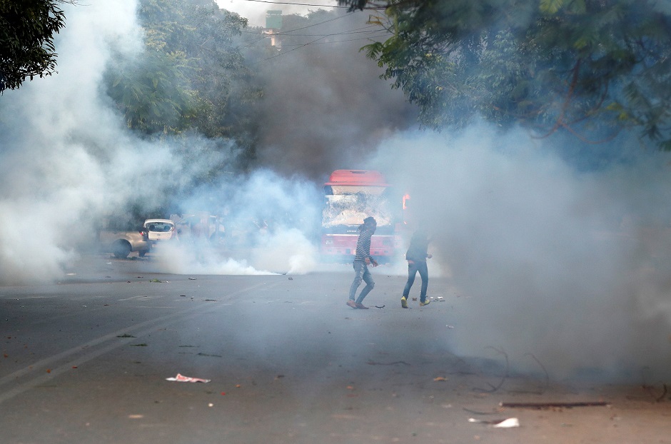 Demonstrators run for cover as smoke billows from a tear gas shell fired. PHOTO: REUTERS 