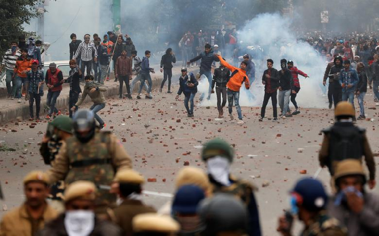 Demonstrators throw pieces of bricks towards riot police during a protest against a new citizenship law in Seelampur, area of Delhi. PHOTO: Reuters