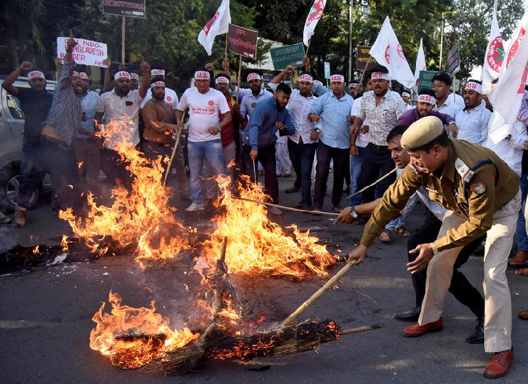 A police officer removes burning effigies that were set on fire by Activists from the All Assam Students Union (AASU) during a protest against the Citizenship Amendment Bill. PHOTO: Reuters