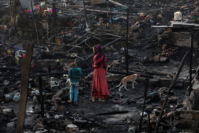 Siblings with their pet dog search for belongings as they visit the burnt-out house of their family after a fire broke out in a slum in Karachi, Pakistan January 22, 2020. REUTERS/Akhtar Soomro