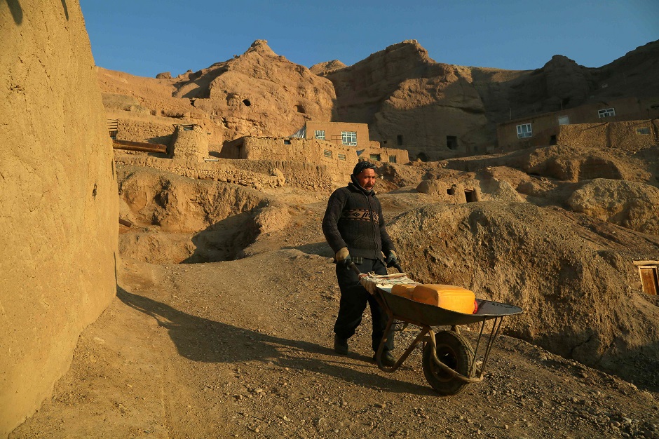 a man carrying water near caves where he lives with his family in Bamiyan. PHOTO: AFP