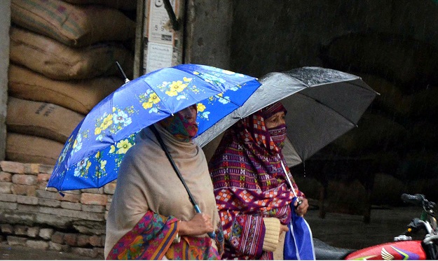 Woman hold umbrellas during heavy rainfall and severe cold in Rawalpindi. PHOTO: INP 
