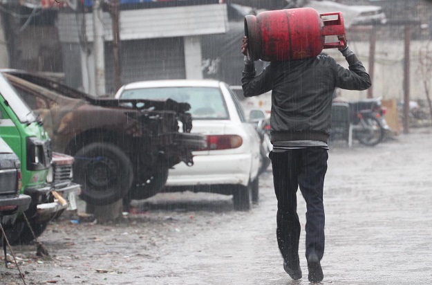 A man carries gas cylinder on his shoulders as cold wind blows in federal capital, Islamabad. PHOTO: ONLINE