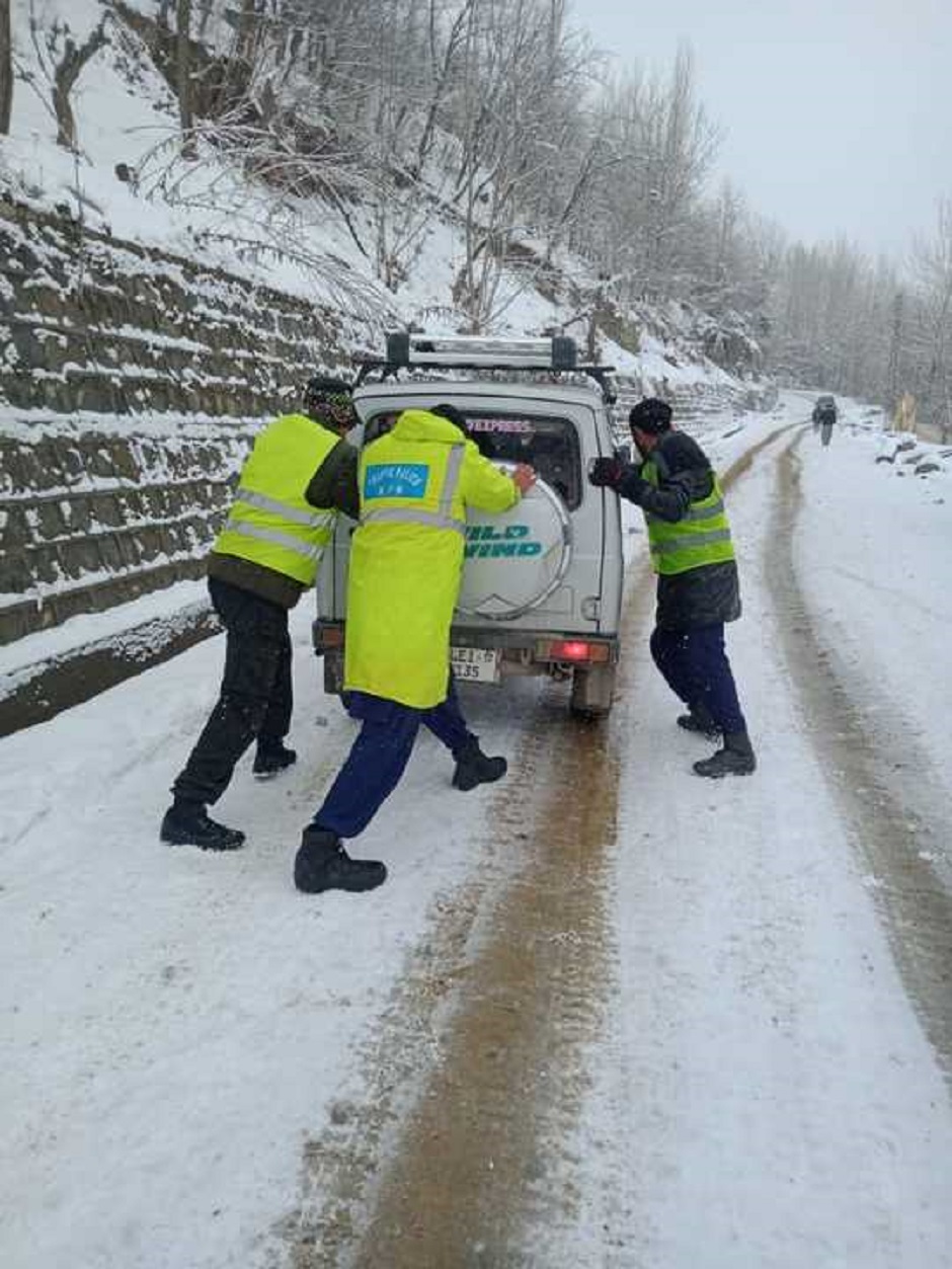 Traffic police personnel help push a vehicle trapped in snow in Chitral. PHOTO: EXPRESS