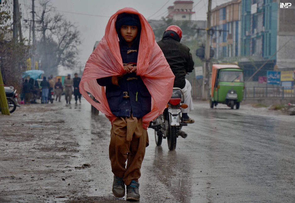 A boy in the way under plastic sheet to protect from rain in Peshawar. PHOTO: INP