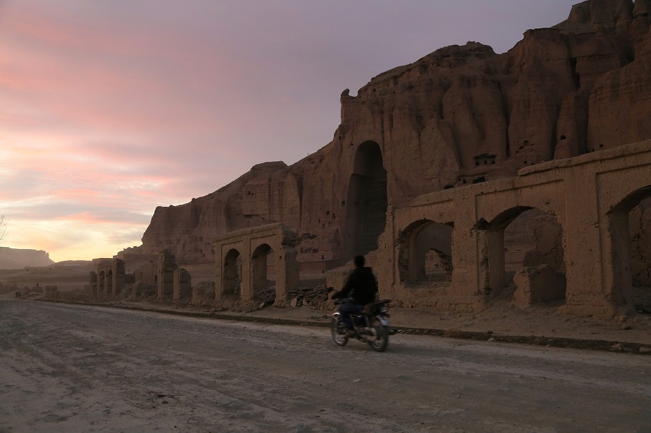 a man riding his motorbike during sunset in front of the empty seat of one of the two Buddha statues destroyed by the Taliban in 2001 in Bamiyan. PHOTO: AFP