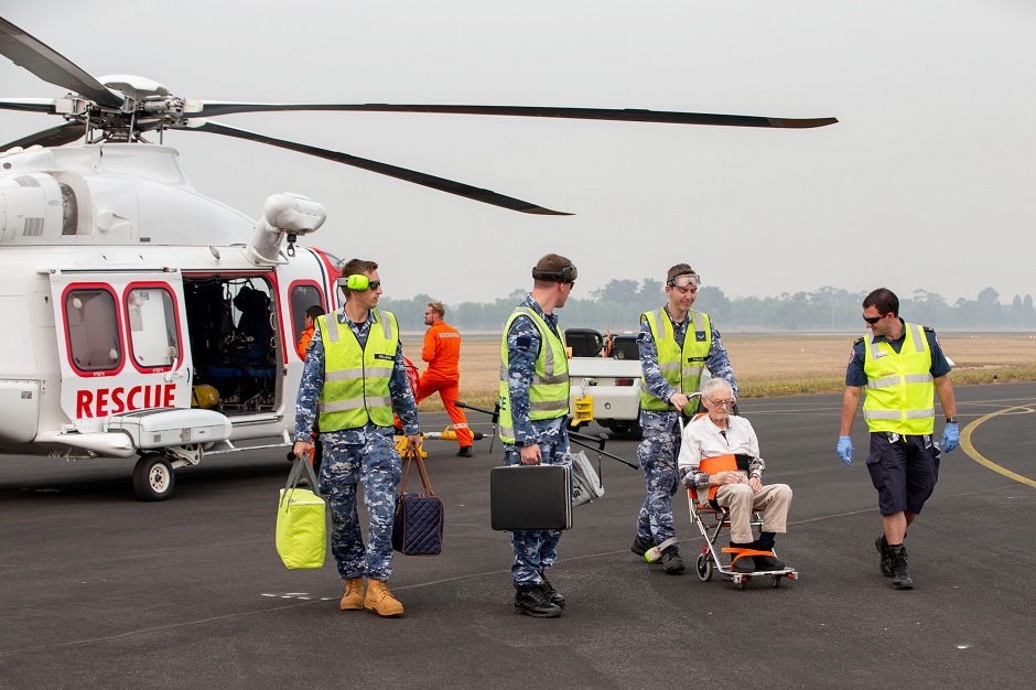 This photo shows RAAF airmen and Victorian paramedic Craig Hooper helping an elderly evacuee off a civilian search and rescue flight that landed at RAAF Base East Sale in Sale, during bushfire relief efforts. PHOTO: AFP.