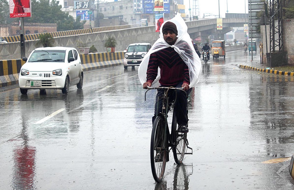 Cyclist on the way under the cover of plastic sheet to protect from rain that experienced in Multan. PHOTO: APP.