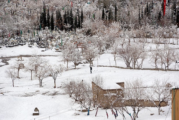 A man walks by a graveyard after heavy snowfall in Quetta. PHOTO: ONLINE