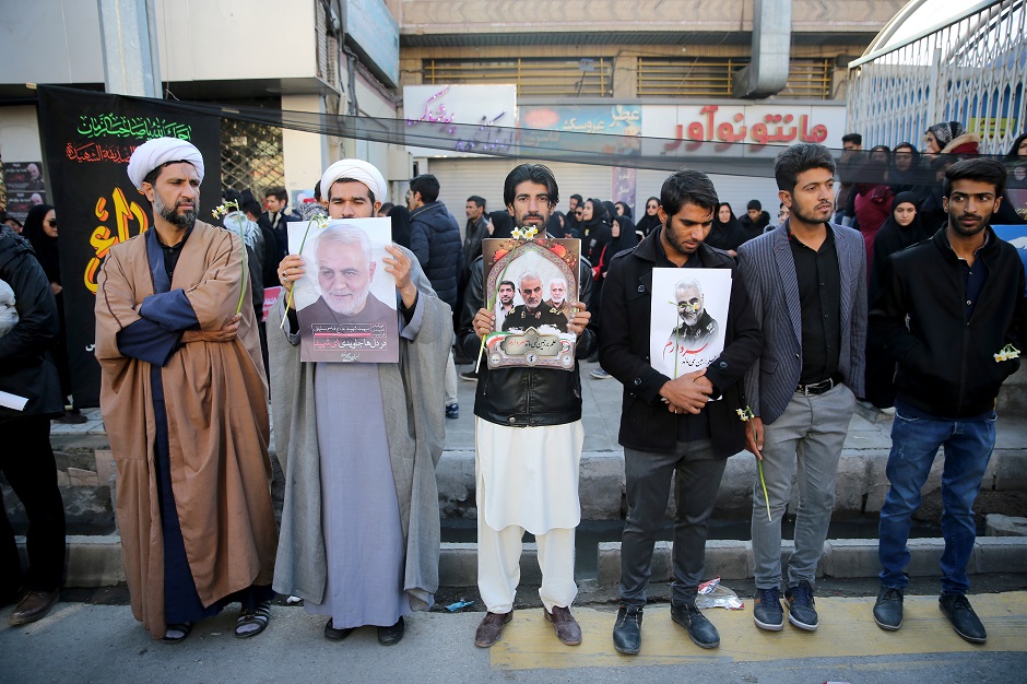 Men hold pictures of Iranian Major-General Qassem Soleimani, head of the elite Quds Force, who was killed in an air strike at Baghdad airport, during a funeral procession and burial at his hometown in Kerman. PHOTO: Reuters