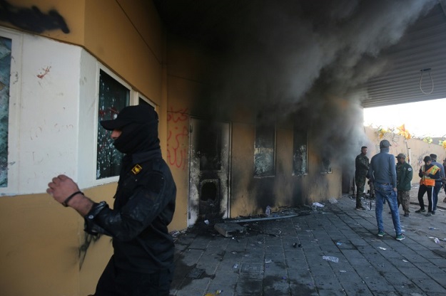 Smoke billows from the entrance of the US embassy in the Iraqi capital Baghdad after supporters and members of the Hashed al-Shaabi military network tried to break into the building, during a rally to vent anger over deadly US air strikes. PHOTO: AFP 