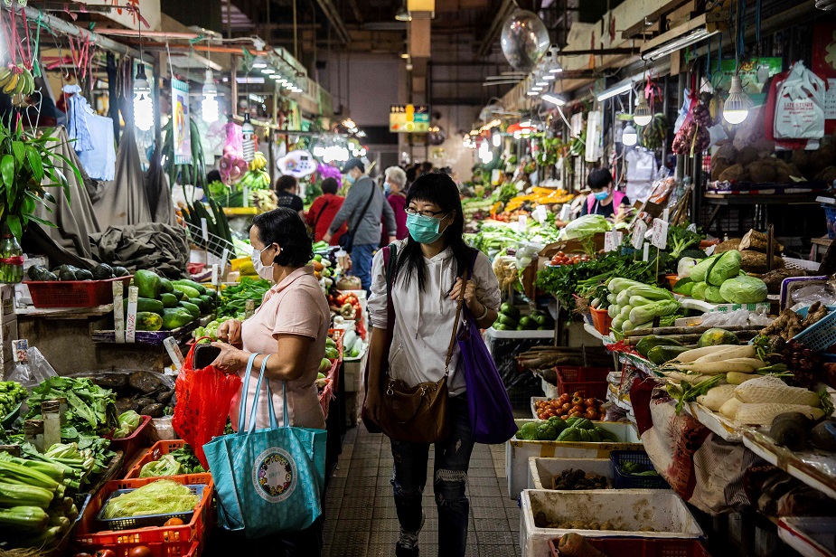 A women (C) walks through the wet markets wearing a protective face mask in Hong Kong on February 25, 2020. - The new coronavirus has peaked in China but could still grow into a pandemic, the World Health Organization warned, as infections mushroom in other countries. PHOTO: AFP